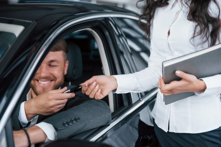 Can't handle emotions. Happy owner of new car sitting inside and takes keys from female manager.